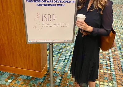 A female doctor smiling next to a conference sign.