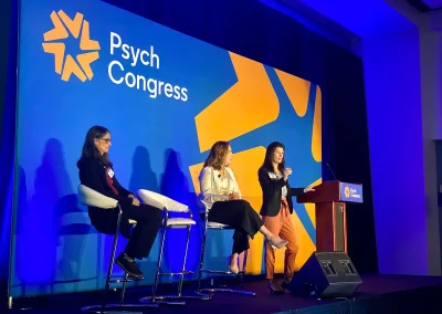 Three women giving a presentation at a conference.