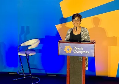 A woman speaking into a microphone at a conference.